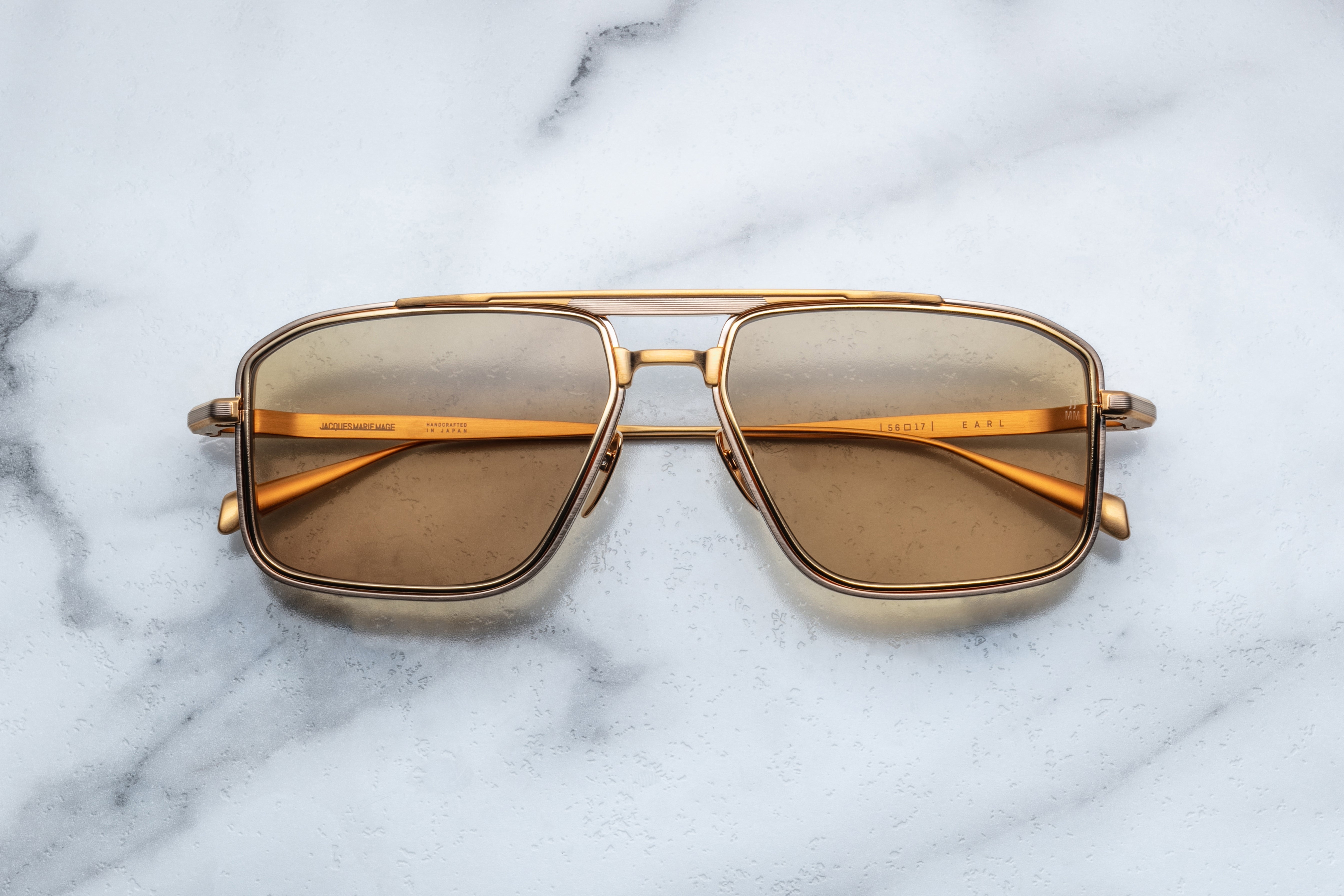 Jacques Marie Mage Earl sunglasses with gold frames, front view showing sleek, modern design and clear lenses.