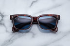Jacques Marie Mage Molino 55 sunglasses with breccia patterned front and dark tinted lenses, close-up view.