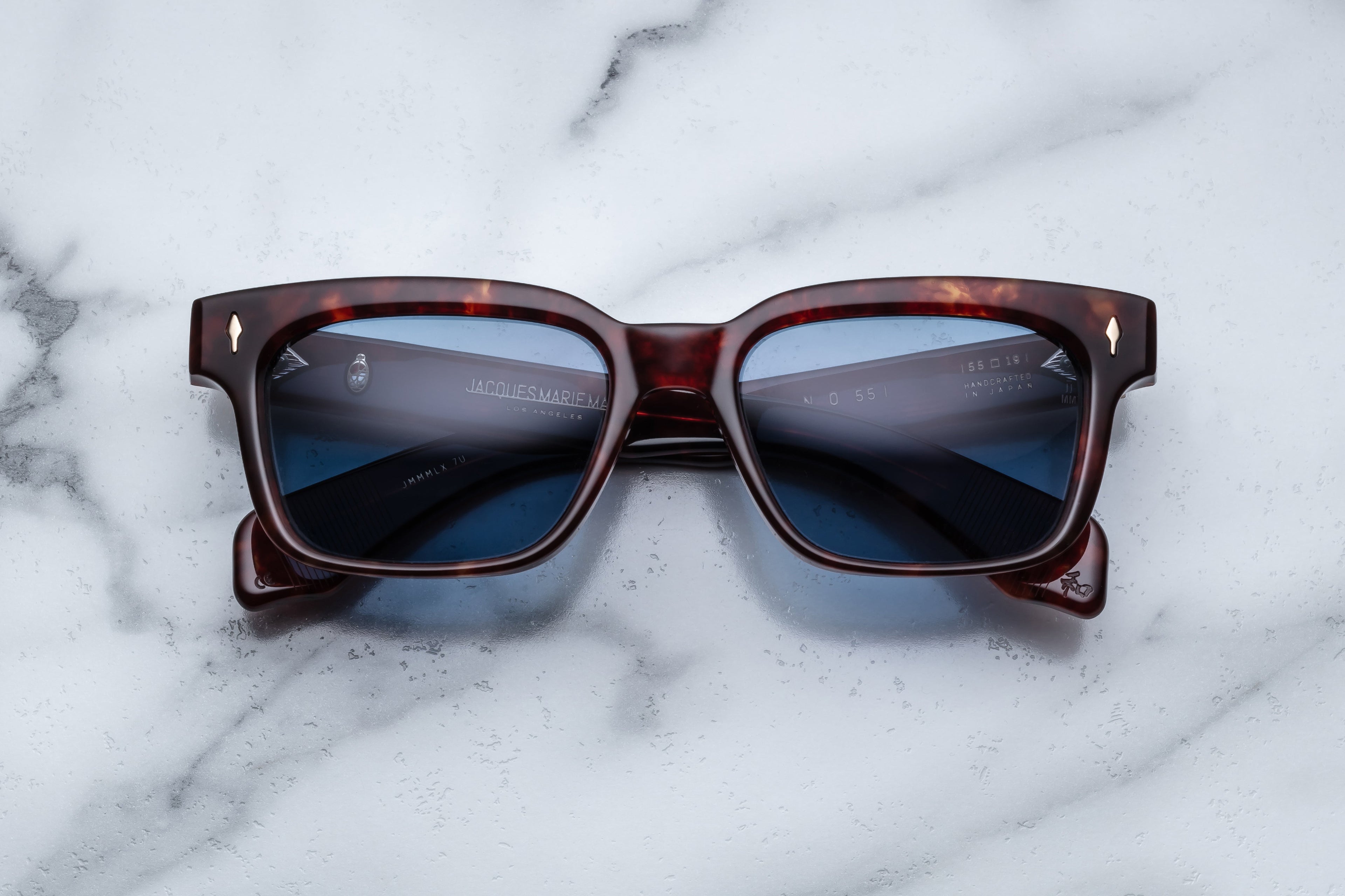 Jacques Marie Mage Molino 55 sunglasses with breccia patterned front and dark tinted lenses, close-up view.