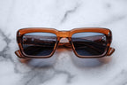 Jacques Marie Mage Walker sunglasses with natural root beer-colored frames and clear lenses, front view showing stylish design.