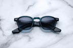 Jacques Marie Mage Zephirin sunglasses with indigo frames and clear lenses, front view showing stylish, modern design.