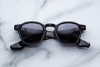Jacques Marie Mage Zephirin Raven sunglasses with round black frames and dark tinted lenses, front view.