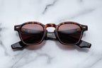 Jacques Marie Mage Zephirin Samoa sunglasses with round frames and dark tinted lenses, close-up front view.